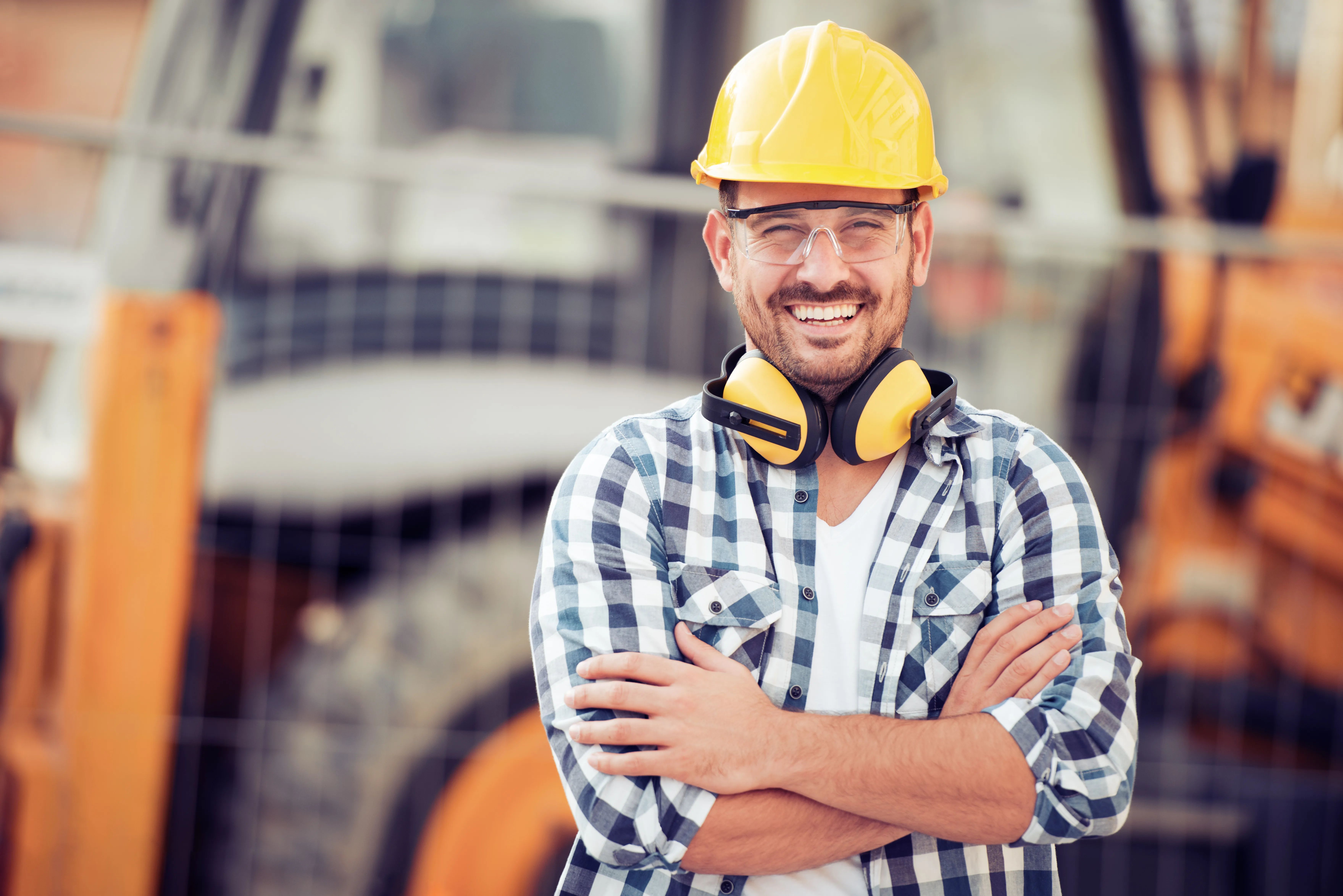 Operaio sorridente con un cantiere sullo sfondo
