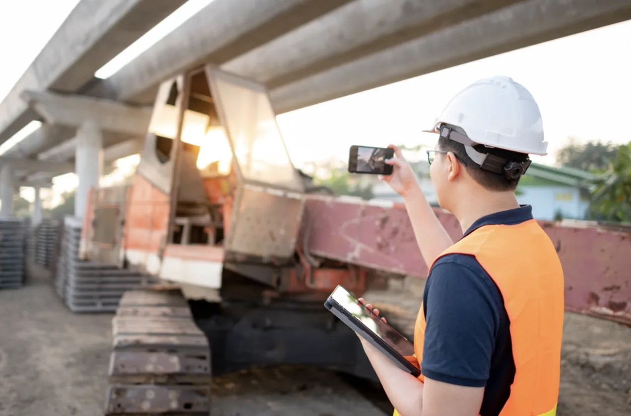 Un uomo in cantiere fotografa con lo smartphone un macchinario
